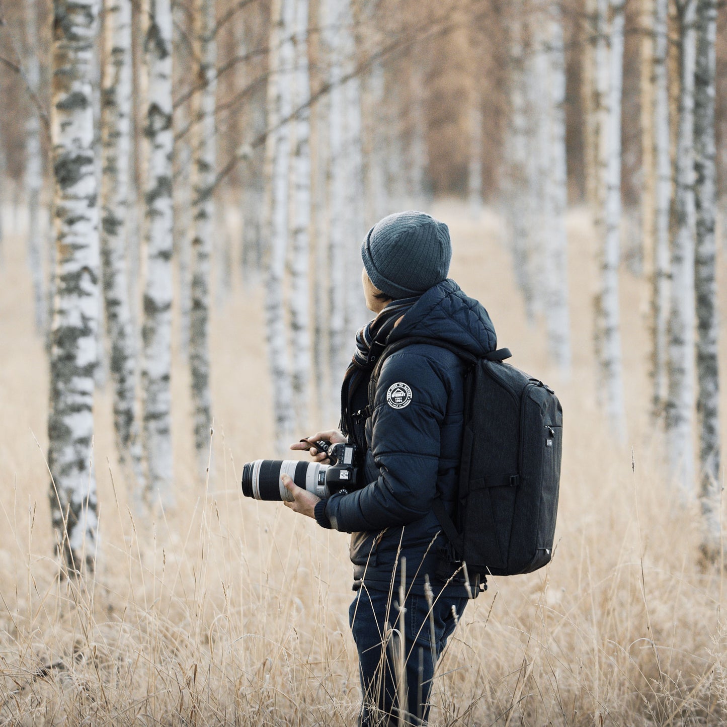 A photographer wearing a backpack and holding camera equipment 